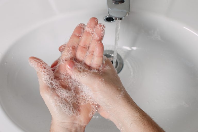 washing hands with soap under faucet.